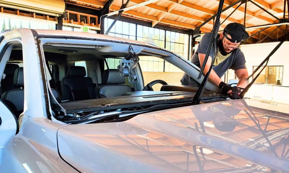 Technician replacing a windshield at the Genesis Auto Glass shop